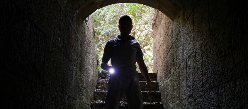 Silhouette Of Person In Tunnel With Flashlight