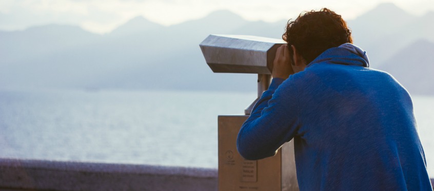 Man Looking Through Telescope at Sea