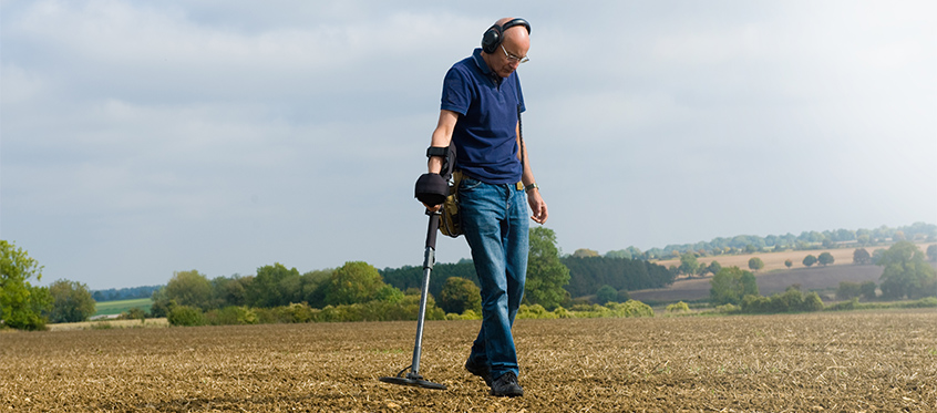 Man Using Metal Detector in Field